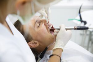 dentist scraping the gum pockets of a patient, cleaning gums to avoid gum disease