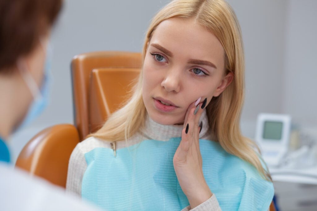 Woman with severe tooth pain in need of emergency dental care