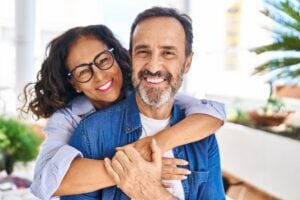 mature couple with their arms around each other showing off their flawless smiles, dental veneers