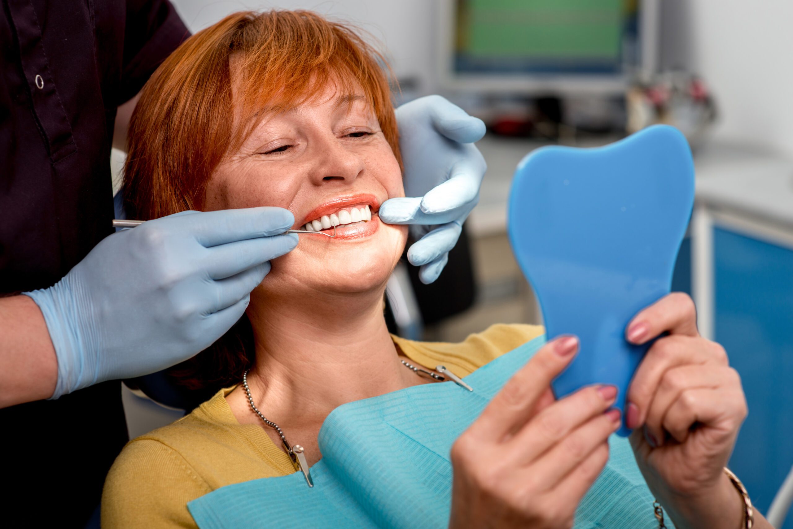 dentist in blue gloves showing a patient her new dental bridge