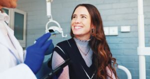 young woman smiling in a dental chair undergoing a consultation