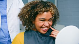 young woman smiling in a mirror in a modern dental office, new dental implants