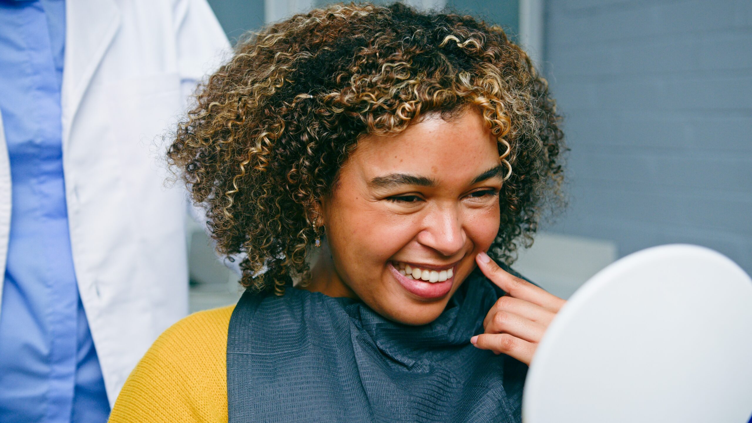 young woman smiling in a mirror in a modern dental office, new dental implants
