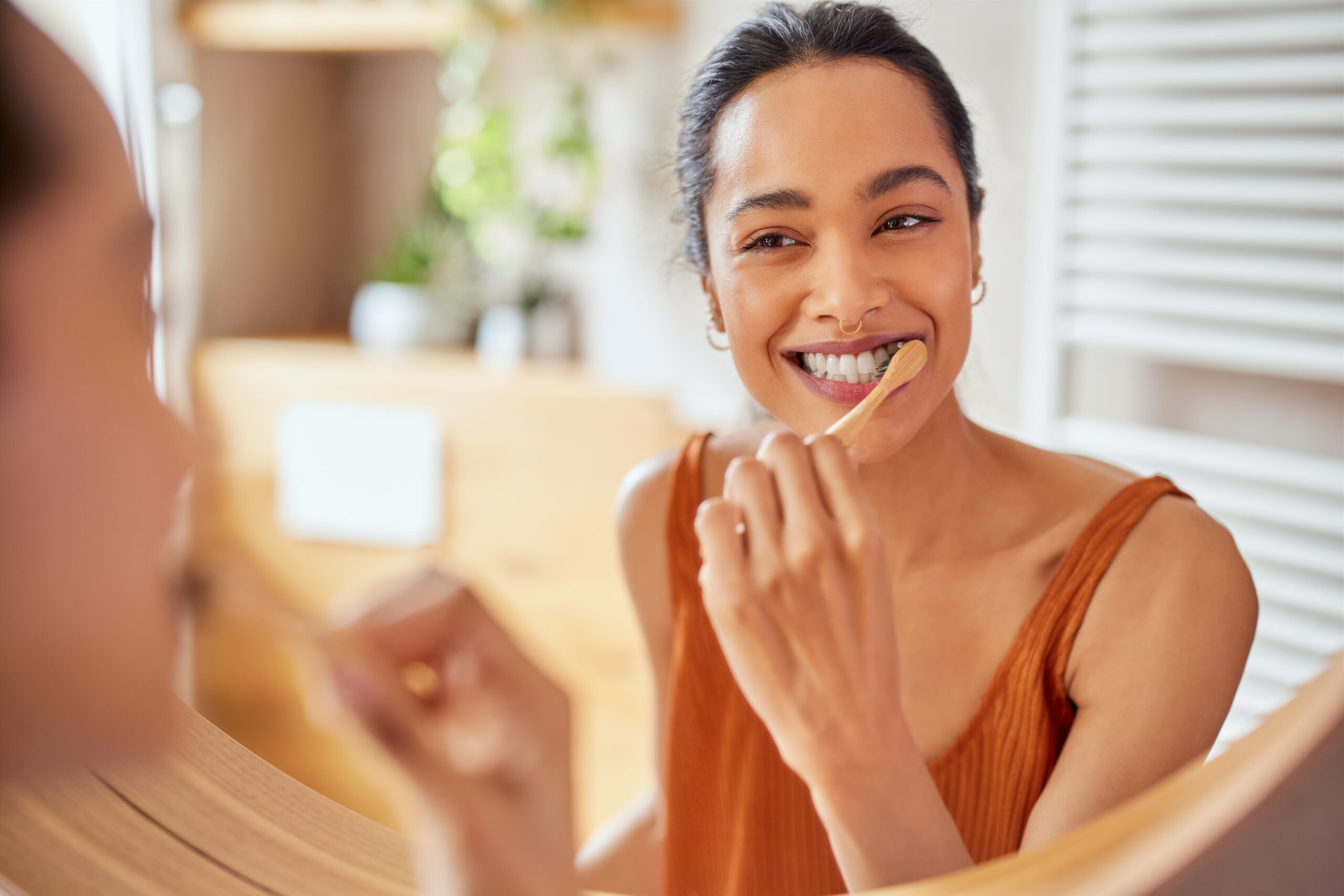 young woman brushing her gums in the mirror