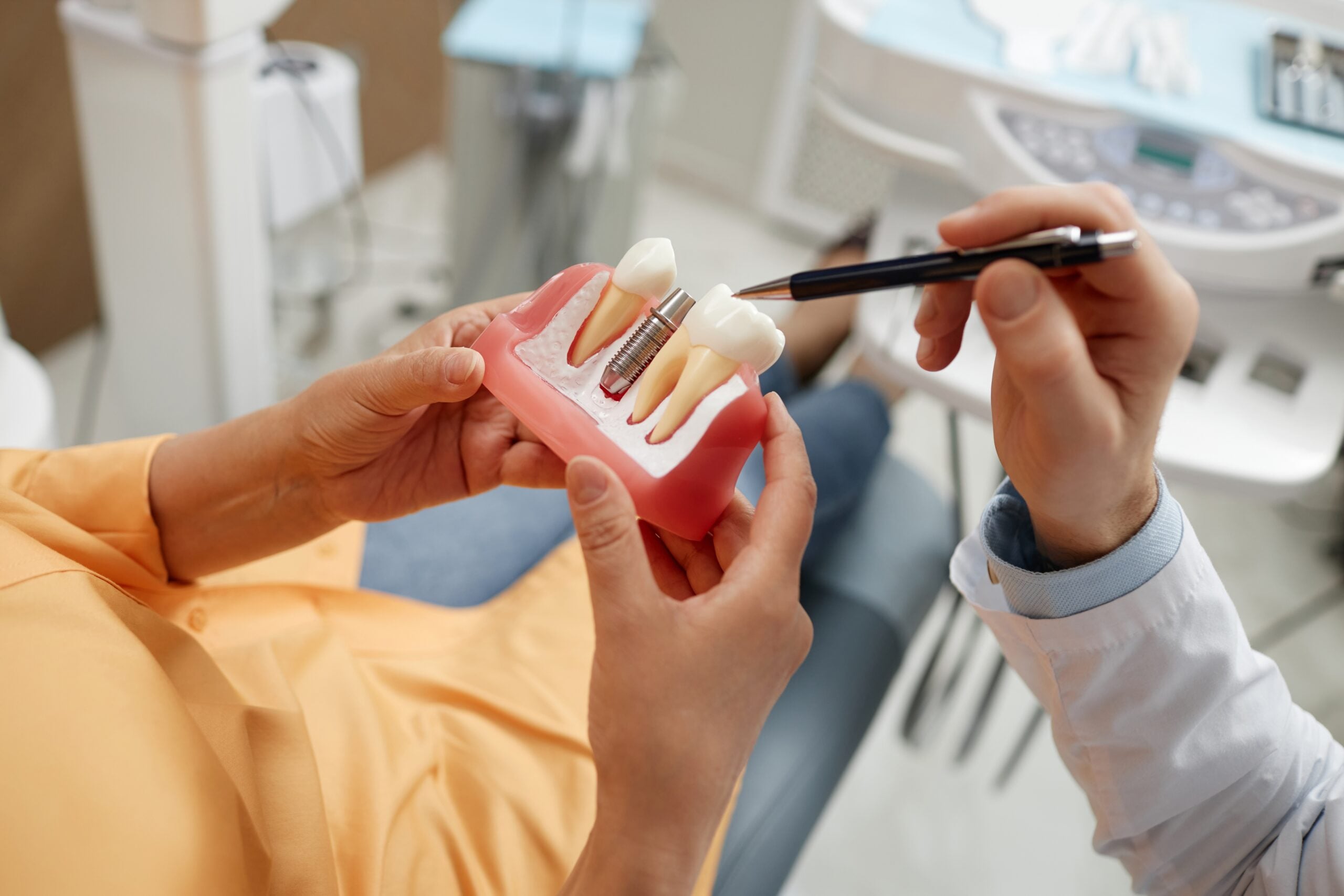 closeup of a dentist showing an implant model to a patient