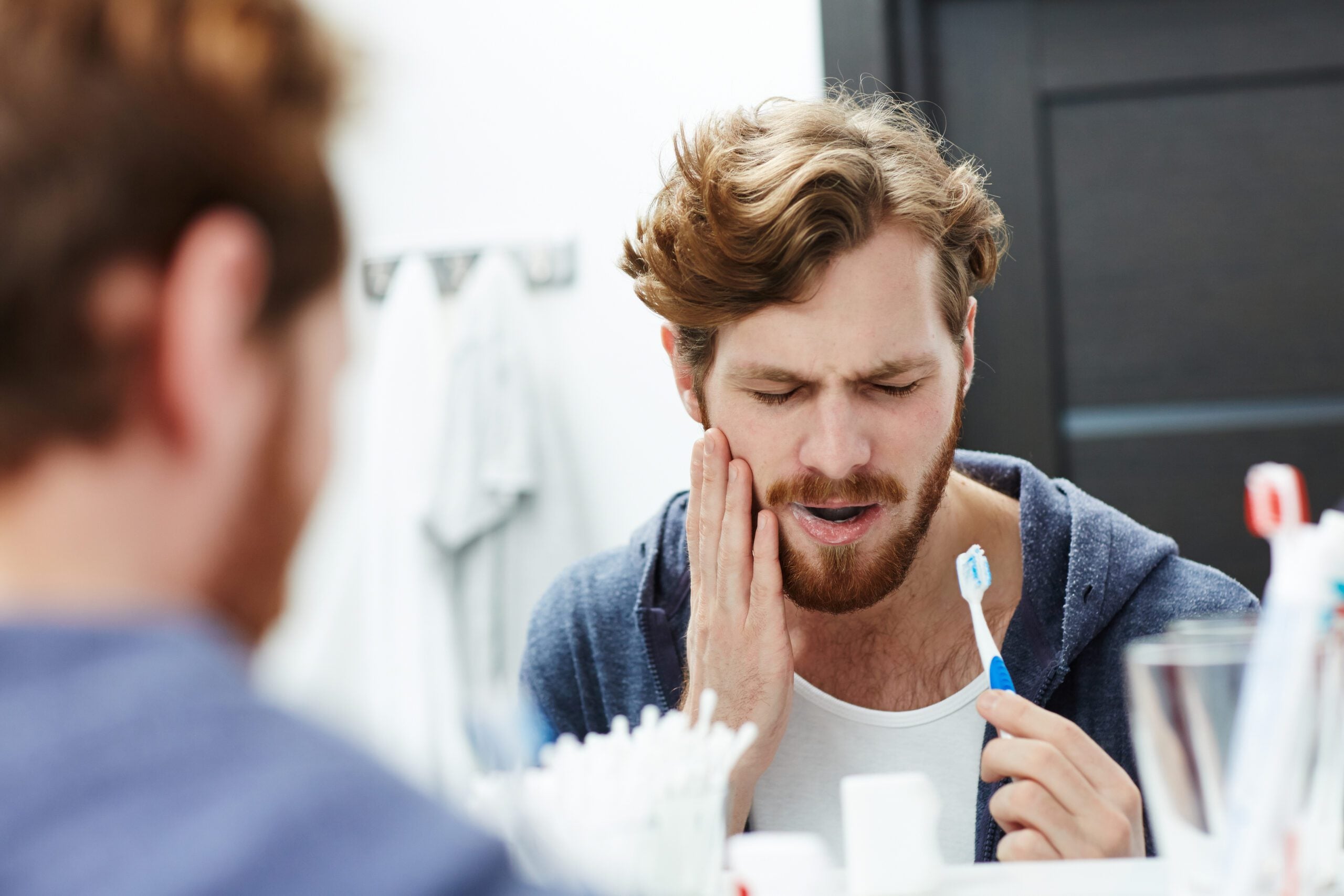 man brushing his teeth in the mirror, sensitive tooth