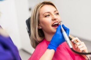 dentist in blue gloves polishing a patients dental crown