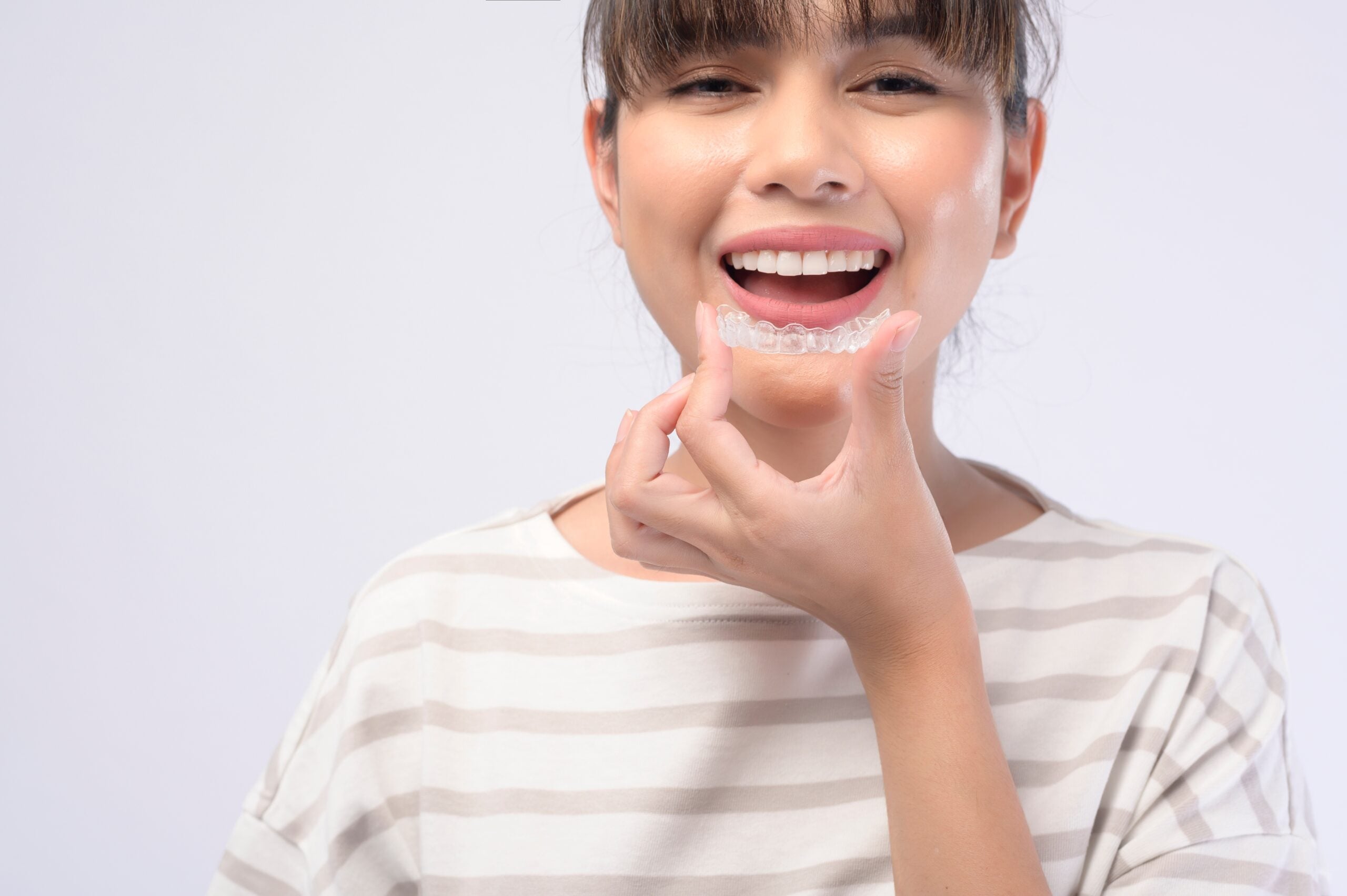 young woman placing clear aligners, white background